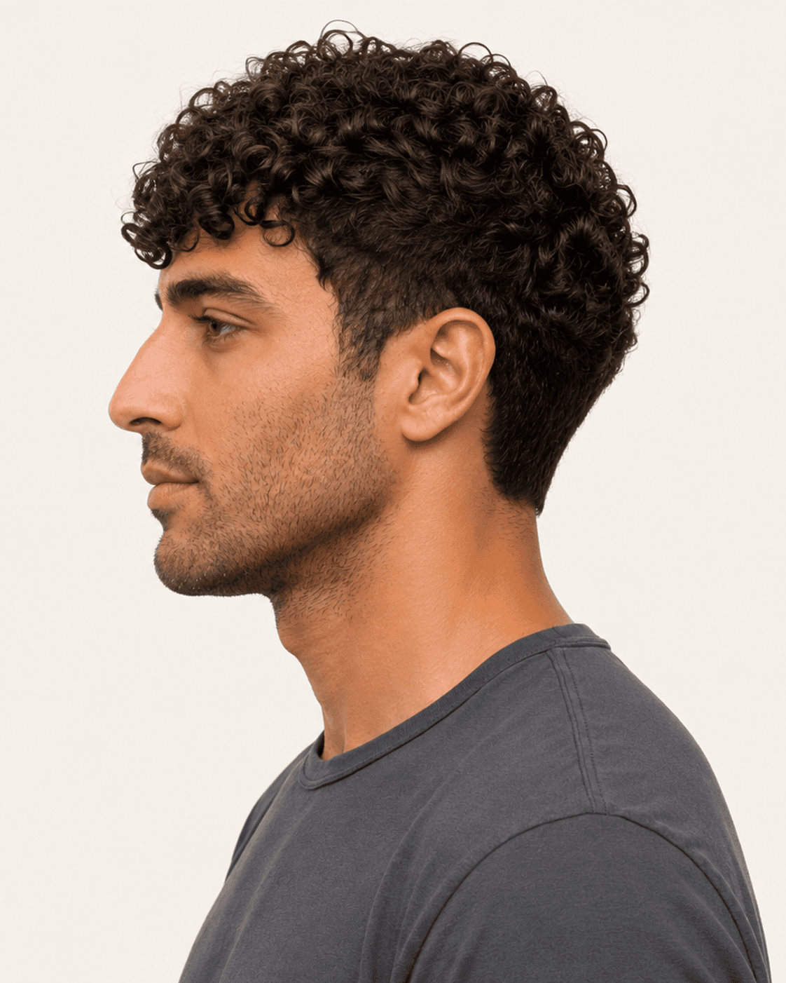 Side profile of a curly fringe crop showing forward fringe projection and a shorter temple field